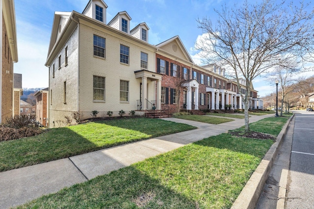 view of property featuring brick siding, a front yard, and a residential view