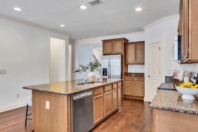 kitchen featuring stainless steel appliances, visible vents, dark wood-type flooring, a sink, and dark stone countertops