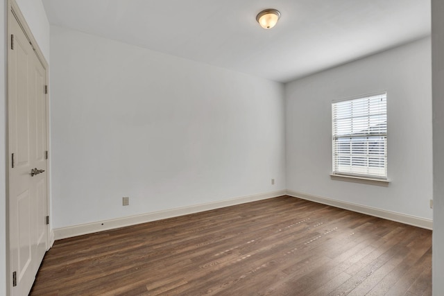 spare room with dark wood-type flooring and baseboards