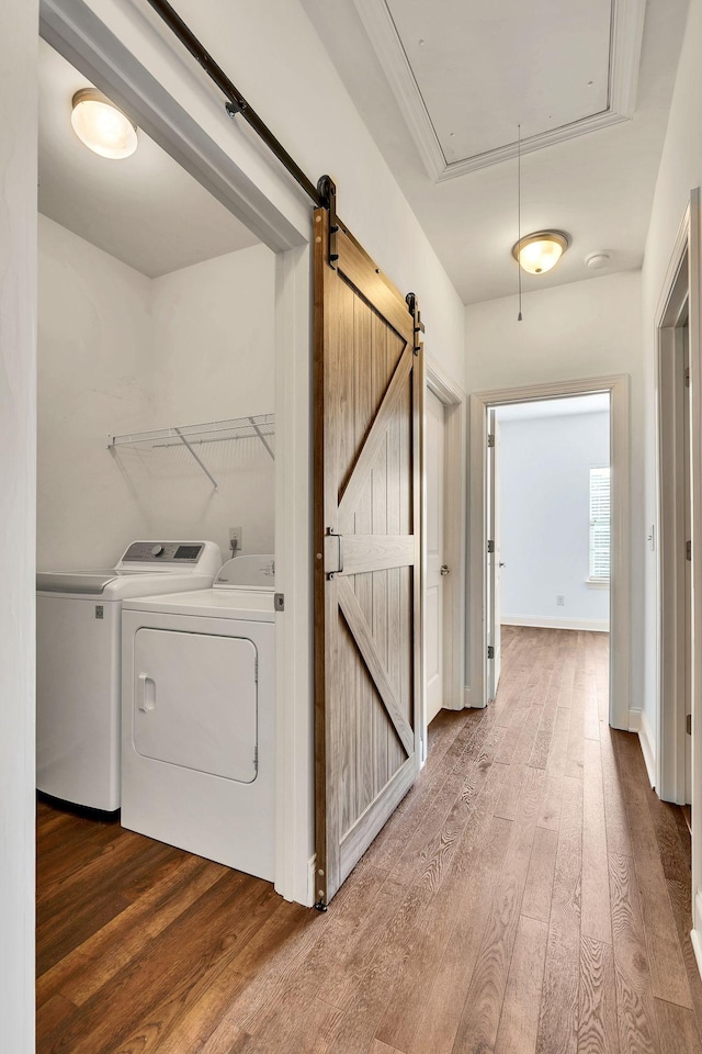 clothes washing area featuring laundry area, attic access, separate washer and dryer, and wood finished floors