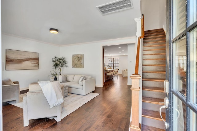 living area featuring dark wood-style flooring, visible vents, crown molding, and stairway