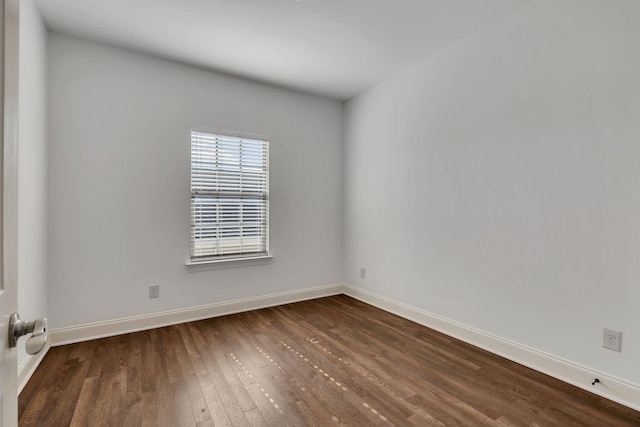 spare room with dark wood-style flooring and baseboards