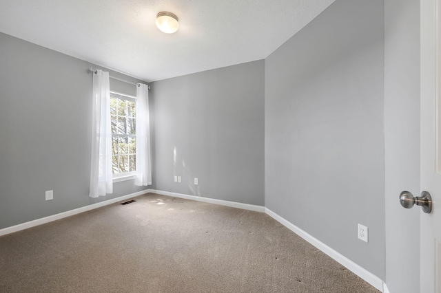 carpeted empty room featuring visible vents and baseboards