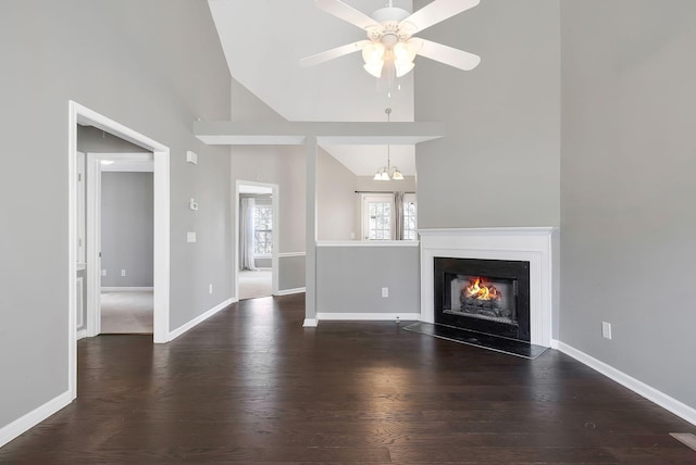 unfurnished living room with baseboards, a ceiling fan, wood finished floors, a lit fireplace, and high vaulted ceiling