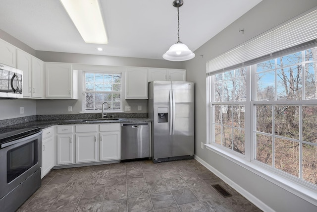 kitchen with appliances with stainless steel finishes, a wealth of natural light, white cabinets, and visible vents