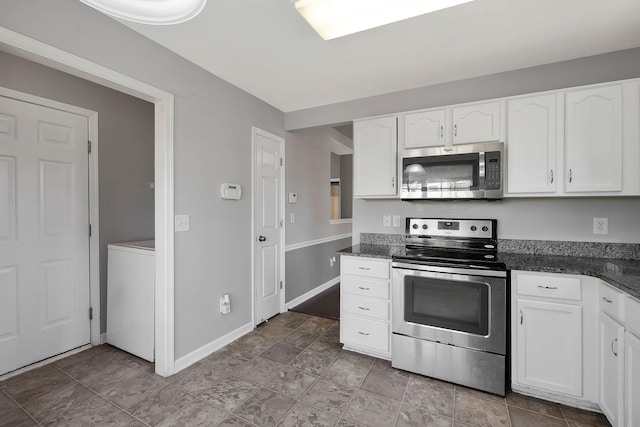 kitchen with stainless steel appliances, baseboards, white cabinets, dark stone counters, and washer / dryer