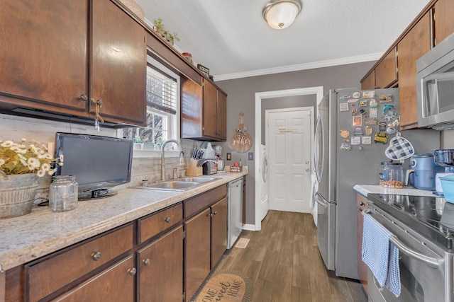 kitchen with dark wood finished floors, crown molding, stainless steel appliances, light countertops, and a sink