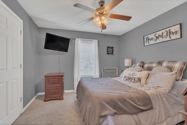 carpeted bedroom featuring a textured ceiling, ceiling fan, and baseboards