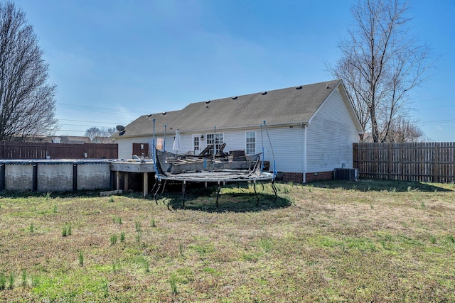 rear view of house with a fenced in pool, a trampoline, central air condition unit, crawl space, and a fenced backyard