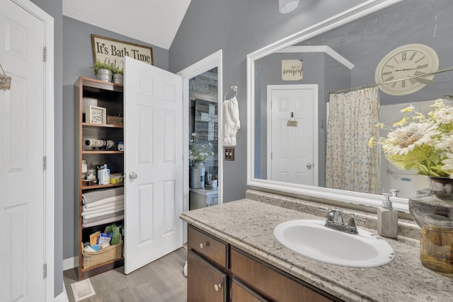 bathroom featuring lofted ceiling, vanity, a shower with shower curtain, and wood finished floors