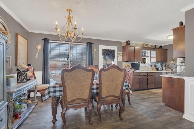 dining room featuring wood finish floors, a wainscoted wall, a textured ceiling, and an inviting chandelier