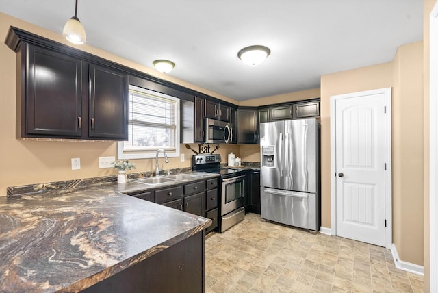 kitchen featuring a sink, baseboards, appliances with stainless steel finishes, dark countertops, and decorative light fixtures