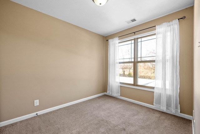 unfurnished room with carpet floors, visible vents, and baseboards