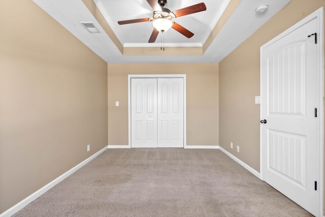 unfurnished bedroom with crown molding, a closet, a raised ceiling, visible vents, and baseboards