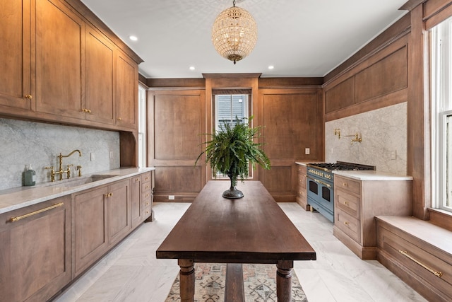 kitchen featuring brown cabinets, a sink, light countertops, double oven range, and backsplash
