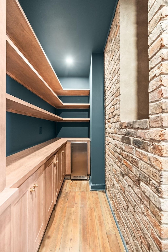 bar with light wood-type flooring and brick wall