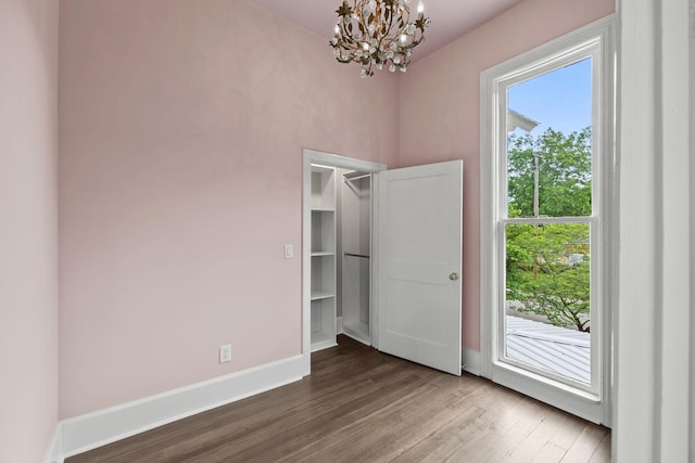 interior space with a notable chandelier, wood finished floors, and baseboards