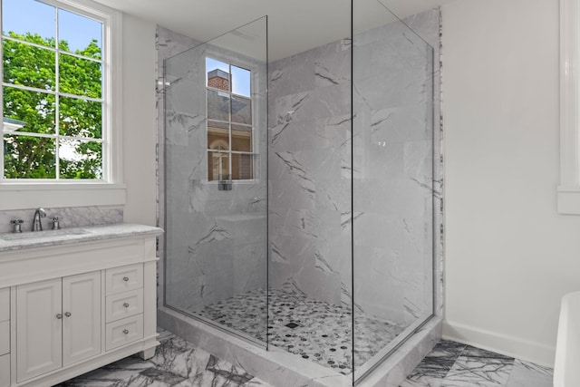 bathroom with marble finish floor, a marble finish shower, vanity, and baseboards