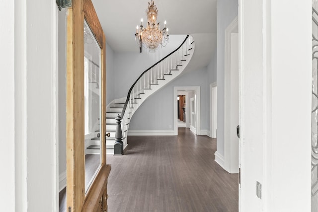 entrance foyer with wood finished floors, a notable chandelier, baseboards, and stairs