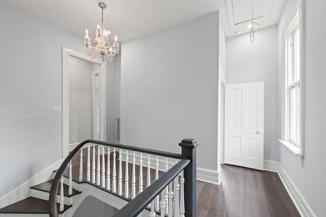 hallway with attic access, baseboards, dark wood finished floors, and an upstairs landing