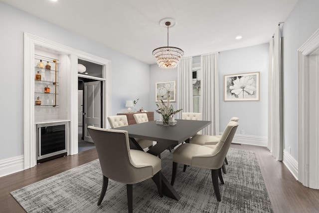 dining space with dark wood-style floors, wine cooler, baseboards, and an inviting chandelier