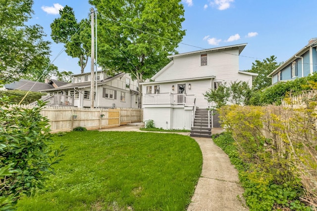 rear view of property with stairway, fence, and a lawn