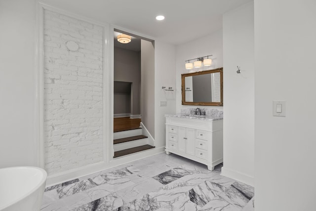 bathroom with marble finish floor, baseboards, a freestanding bath, and vanity