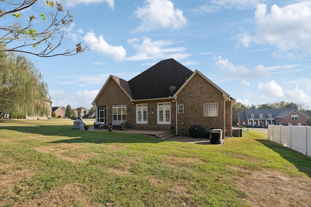 rear view of property with a yard, french doors, fence, and brick siding