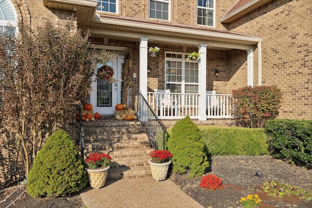 doorway to property with a porch and brick siding