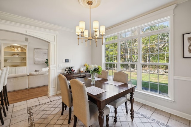 dining space with a chandelier, built in shelves, light tile patterned flooring, baseboards, and crown molding