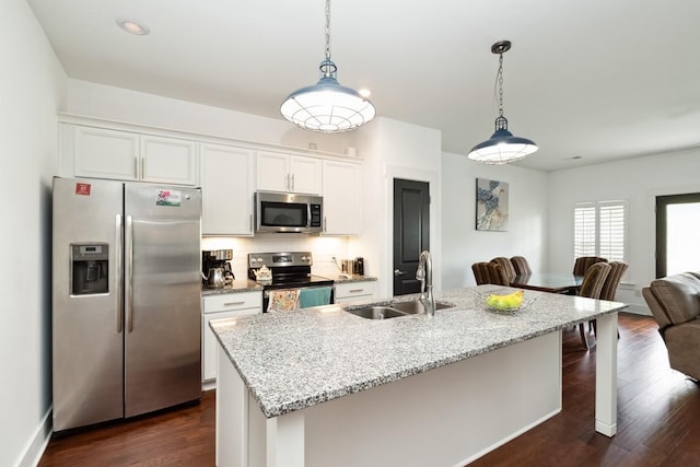 kitchen featuring stainless steel appliances, a sink, white cabinetry, open floor plan, and dark wood finished floors