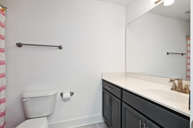 bathroom featuring toilet, vanity, visible vents, and baseboards