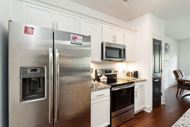 kitchen featuring stainless steel appliances, dark wood-type flooring, white cabinets, decorative backsplash, and light stone countertops