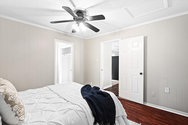 bedroom featuring attic access, dark wood finished floors, ceiling fan, ornamental molding, and a textured ceiling