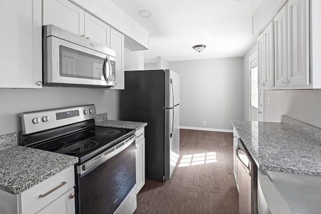 kitchen with stainless steel appliances, dark wood-type flooring, white cabinetry, and light stone counters