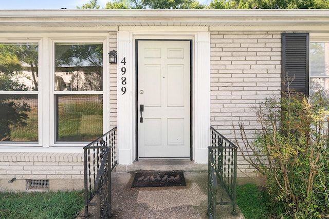 view of exterior entry featuring brick siding and crawl space