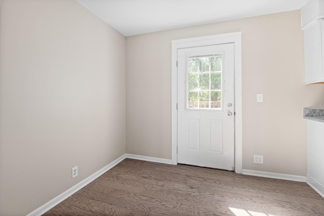 doorway to outside featuring baseboards and wood finished floors