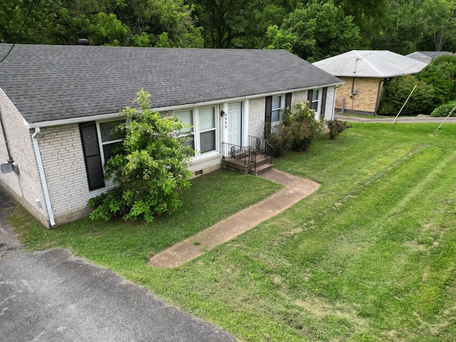 single story home with a shingled roof, a front lawn, and brick siding