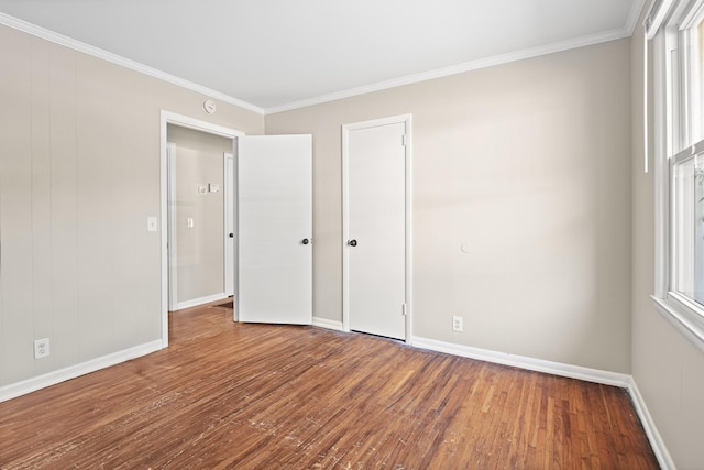 unfurnished bedroom with a closet, crown molding, baseboards, and hardwood / wood-style flooring