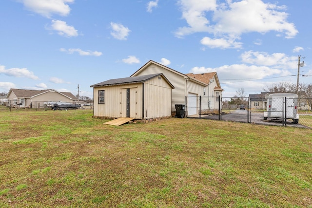 rear view of property featuring an outbuilding, a lawn, fence, and a gate