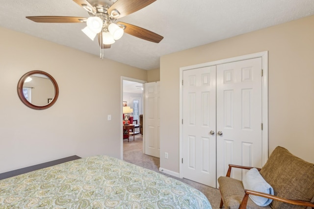 bedroom featuring a closet, a ceiling fan, light carpet, a textured ceiling, and baseboards