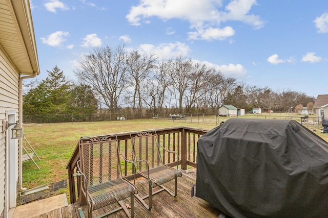 wooden deck featuring a grill, an outbuilding, a lawn, and a fenced backyard