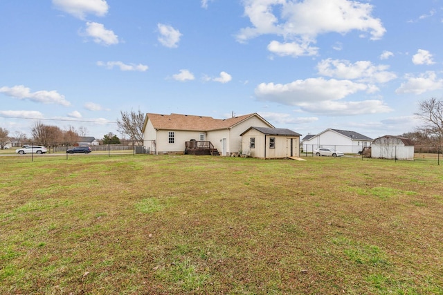 back of house with an outbuilding, a yard, a storage unit, and fence