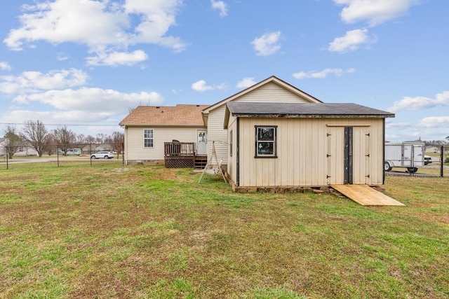 rear view of house with an outdoor structure, a yard, and a wooden deck