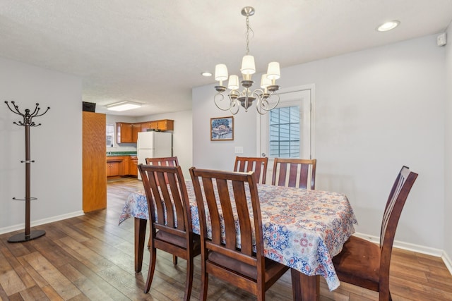 dining space with recessed lighting, wood-type flooring, a notable chandelier, and baseboards