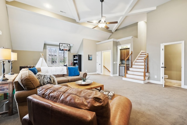 living room with baseboards, a ceiling fan, beamed ceiling, stairs, and light carpet