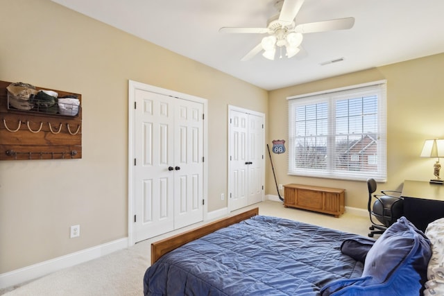 bedroom featuring ceiling fan, visible vents, carpet floors, multiple closets, and baseboards