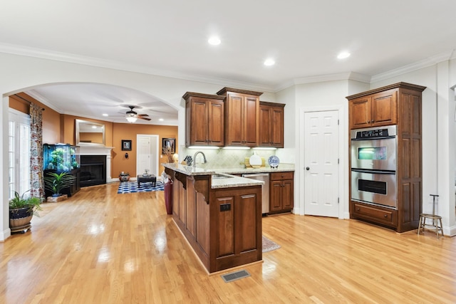 kitchen with a peninsula, a ceiling fan, visible vents, stainless steel appliances, and arched walkways