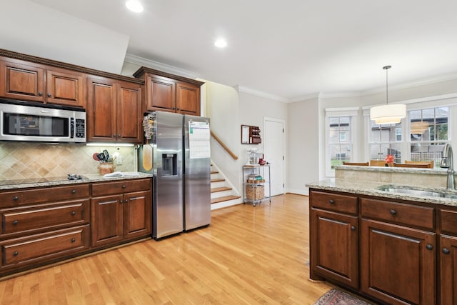 kitchen with a sink, light wood-type flooring, crown molding, and stainless steel appliances