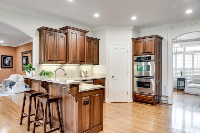 139 Thornwood Pl, Hendersonville, TN 37075 - kitchen featuring appliances with stainless steel finishes, light wood-style floors, arched walkways, a kitchen breakfast bar, and a peninsula